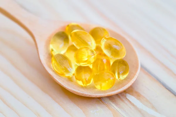 Capsule di olio di pesce con omega 3 e vitamina D su legno di cucchiaio con sfondo in legno, concetto di dieta sana . — Foto Stock