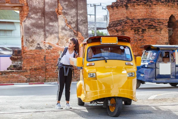 Traveler japanese girl hollding map travel query for the way with old man driver taxi or tuk tuk touring, Ayutthaya Province, Thailand