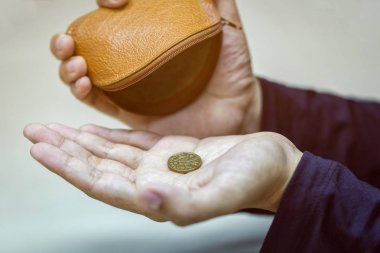 Hands holding one dollar coin and small money pouch. clipart