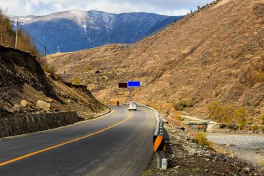 Araba ve motosiklet yolun altında kar dağ Sichuan, Çin Tibet güzel kış yolu üzerinde