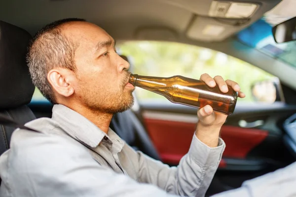酔ってアジアの若者は日没の背景を持つビールのボトルで車を運転し 危険な運転の概念 — ストック写真