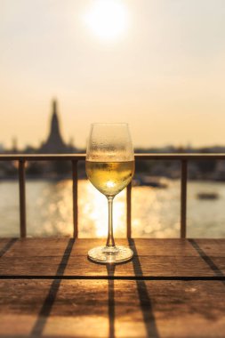 Chao Phraya Nehri ve Wat Arun arka plan görünümünü günbatımı üzerinde bar ve restoran ile kadeh şarap, Bangkok, Tayland