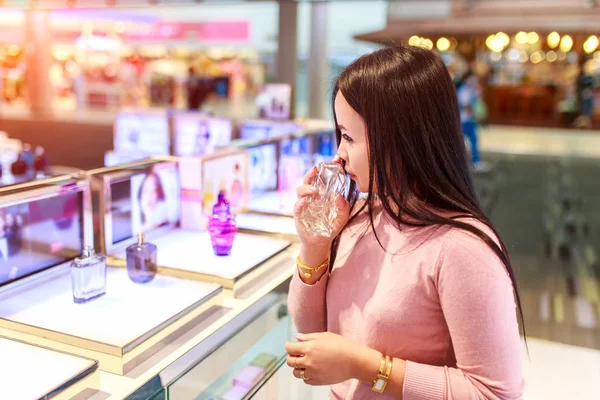 Genç Asyalı kadın test ve parfüm Uluslararası Havaalanı'nda duty free mağazasında satın almak için seçin.