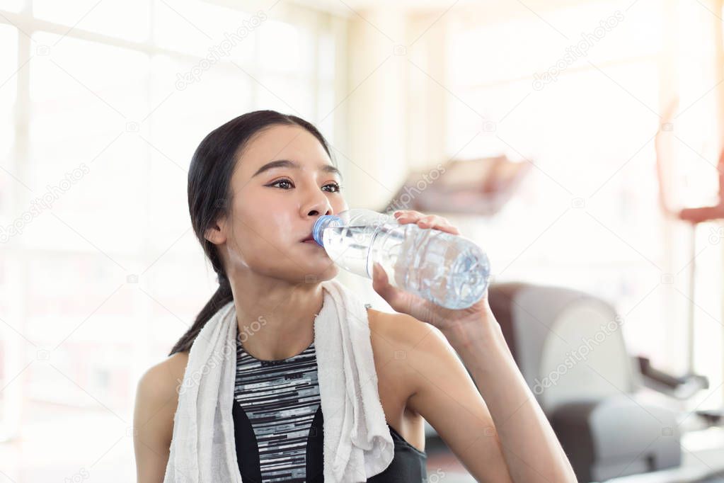 Pretty sporty young asian woman drinking water after sport train