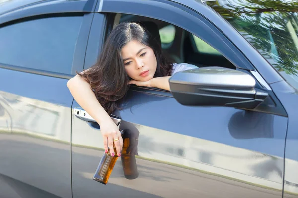 Joven asiática bebiendo cerveza mientras conduce un coche — Foto de Stock