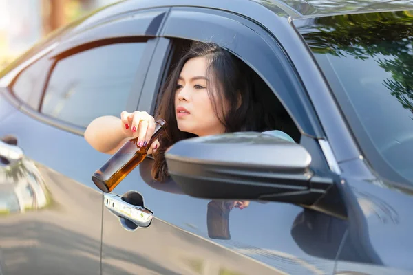 Joven asiática bebiendo cerveza mientras conduce un coche — Foto de Stock