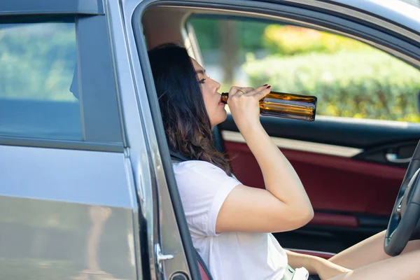 Joven asiática bebiendo cerveza mientras conduce un coche — Foto de Stock