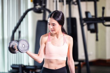 Genç Asyalı kadın spor salonunda halterle egzersiz yapıyor..