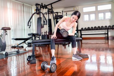 Genç Asyalı kadın spor salonunda halterle egzersiz yapıyor..