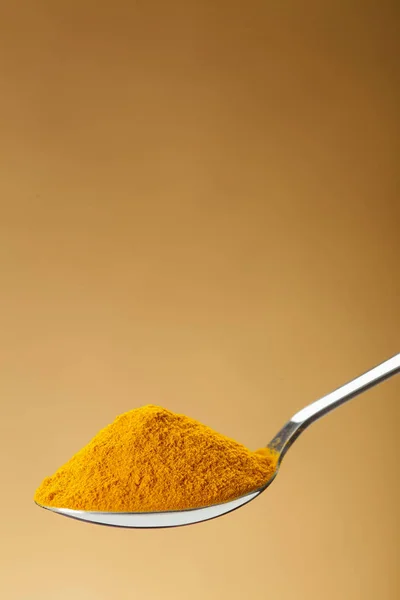 Spoon of ground turmeric on yellow background — Stock Photo, Image