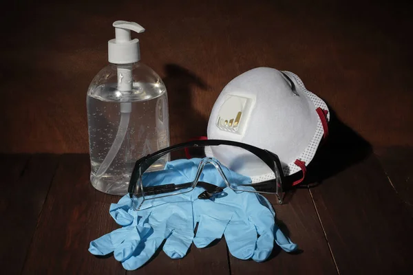 recommended personal protection kit formed by hygiene gel, medical mask, nitrile gloves and security glasses to prevent contagion by bacteria and virus. all over wooden ground and background