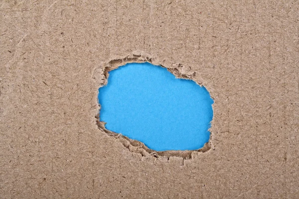 Roztrhl díru s modrý papír v kartonu — Stock fotografie