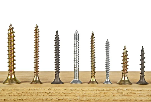 Various screws on wooden plank on a white background — Stock Photo, Image