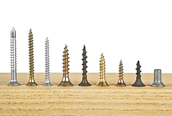 Beyaz bir arka plan üzerinde ahşap tahta üzerinde çeşitli vida