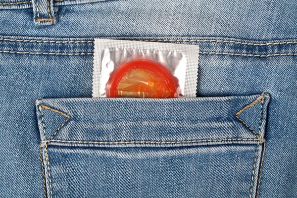 Preservativo vermelho no bolso de calça azul — Fotografia de Stock