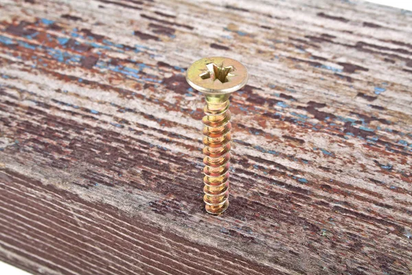 Golden screw screwed into old wooden plank, white background — Stock Photo, Image