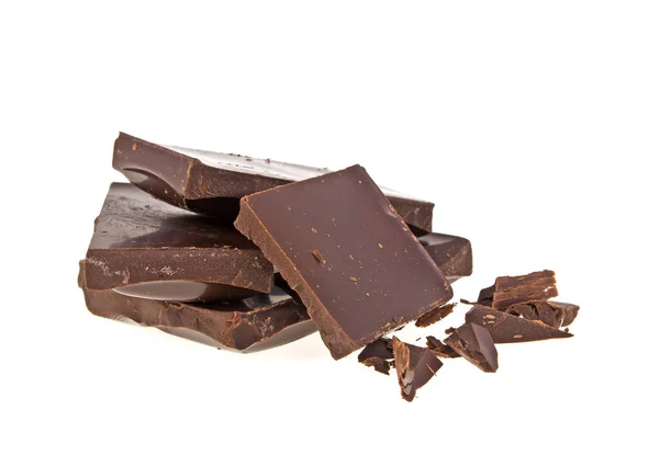 Heap de pedaços quebrados de chocolate no fundo branco — Fotografia de Stock