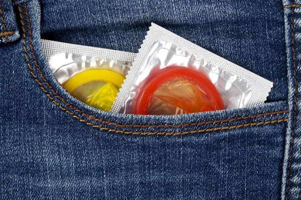 Preservativos coloridos em um bolso de calça azul — Fotografia de Stock