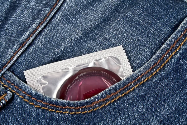 Preservativo colorido em um bolso de calça azul — Fotografia de Stock