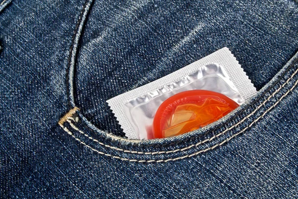 Preservativo vermelho no bolso de calça azul — Fotografia de Stock