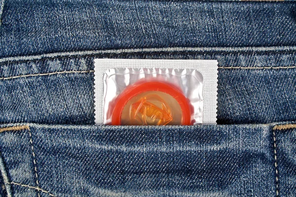 Farvet kondom i en blå jeans lomme - Stock-foto