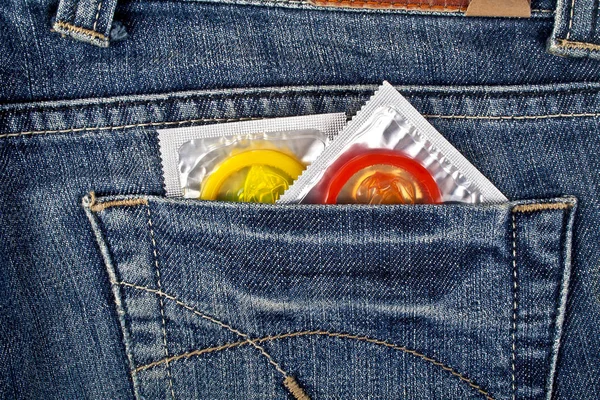 Colored condoms in a blue jeans pocket — Stock Photo, Image