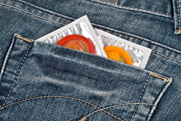 Preservativos coloridos em um bolso de calça azul — Fotografia de Stock