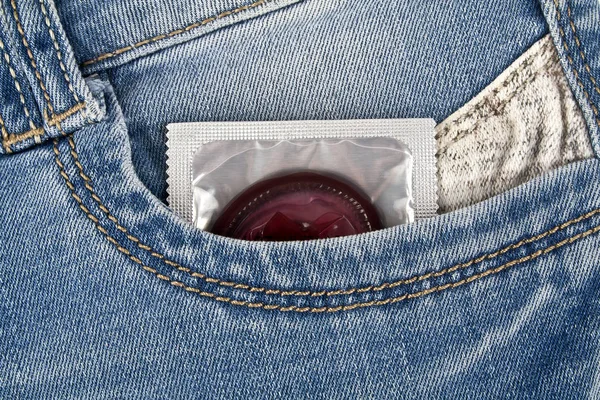 Colored condom in a blue jeans pocket — Stock Photo, Image