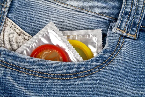 Colored condoms in a blue jeans pocket — Stock Photo, Image