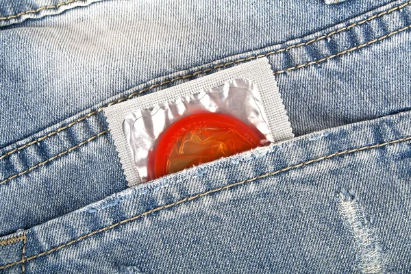 Red condom in blue jeans pocket — Stock Photo, Image