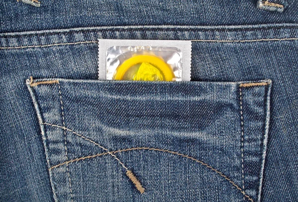 在蓝色的牛仔裤口袋里的彩色的避孕套 — 图库照片
