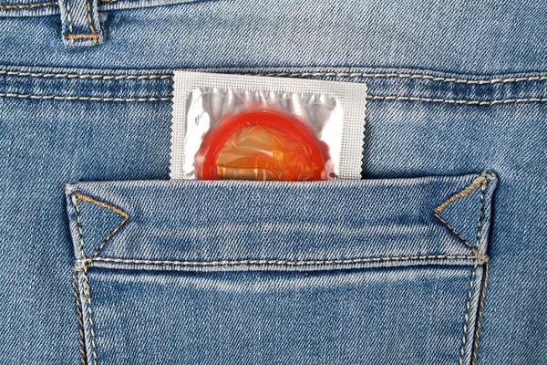 Red condom in blue jeans pocket — Stock Photo, Image