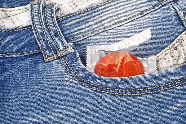 Preservativo vermelho no bolso de calça azul — Fotografia de Stock