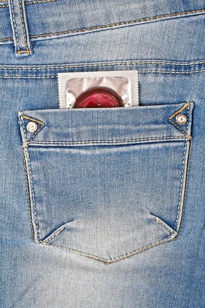 Preservativo colorido em um bolso de calça azul — Fotografia de Stock