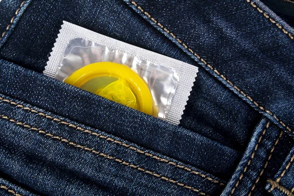 Yellow condom in a blue jeans pocket — Stock Photo, Image