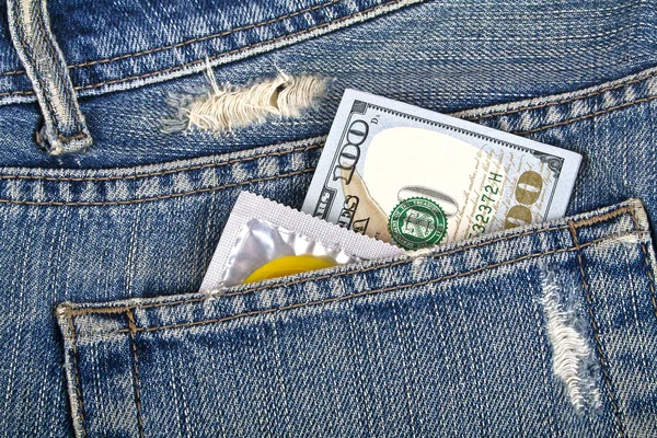 Condón amarillo y cien dólares en un bolsillo azul — Foto de Stock