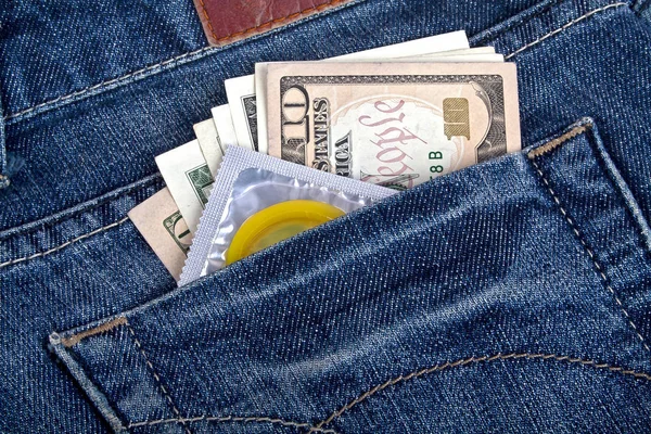 Condón amarillo y dólares americanos en un bolsillo azul — Foto de Stock