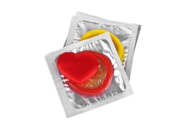 Стек кольорових презервативів і червоне серце на білому тлі — стокове фото