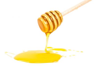 Tahta bir sopa üzerinde beyaz backgro izole dan aşağı akan bal