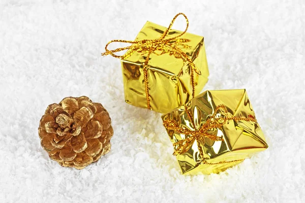 Κουτιά Χριστούγεννα χρυσό και χρυσό κουκουνάρι στο χιόνι — Φωτογραφία Αρχείου