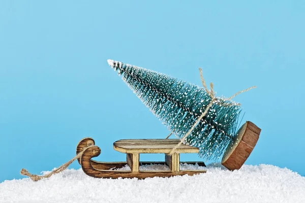 Χριστουγεννιάτικη σύνθεση. Ξύλινο έλκηθρο και το χριστουγεννιάτικο δέντρο σε ένα blu — Φωτογραφία Αρχείου