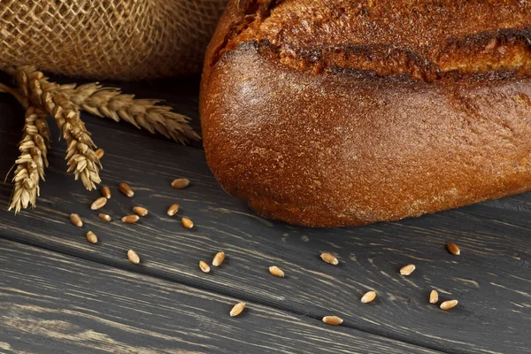 Frisches Brot und Weizen auf Holztisch — Stockfoto