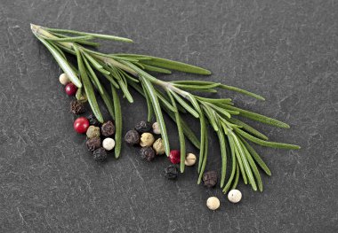 Biberiye ve karabiber siyah taş masada. C için malzemeler