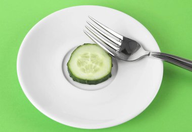 Taze yeşil backgr çatalı ile beyaz tabakta salatalık dilim