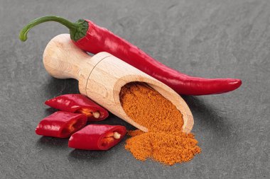 Kırmızı biber biber ve siyah taş masada tahta kaşık toz