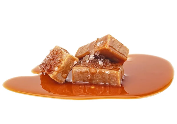 Deliciosos caramelos con sal y salsa de caramelo sobre fondo blanco — Foto de Stock