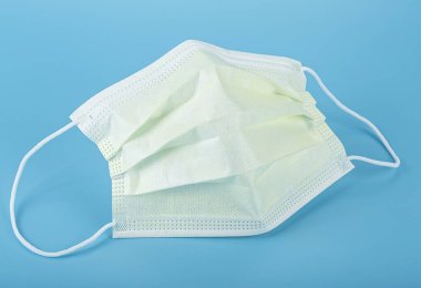 Mavi arka planda sarı tıbbi maske. Lastik kulaklıklı cerrahi maske..