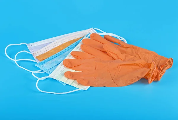 保護コンセプト 青の背景にオレンジ色のラテックス医療手袋と色の外科用マスクのペア — ストック写真