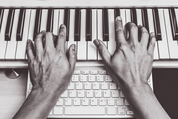 composer hands working on piano keys & computer keyboard