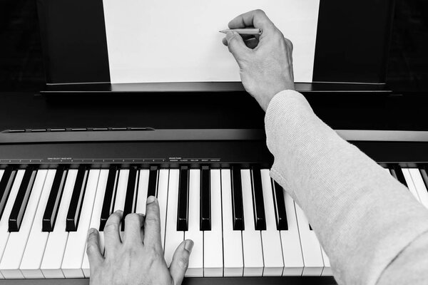 male pianist, composer, songwriter hands writing music & songs on white music sheet